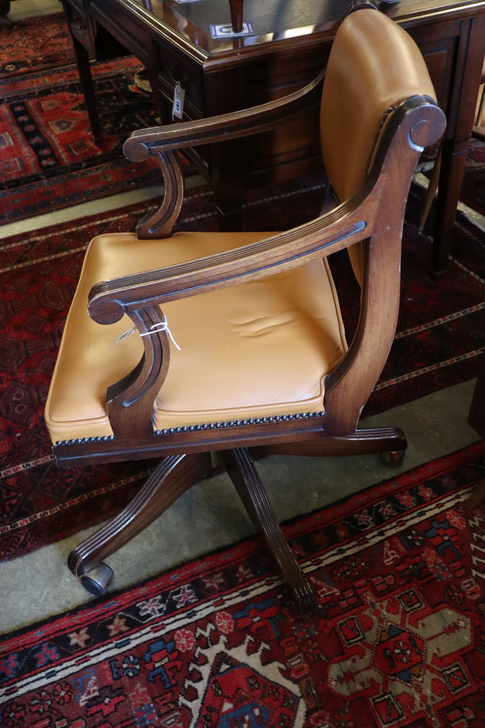 A Reprodux mahogany and tan leather swivel desk chair